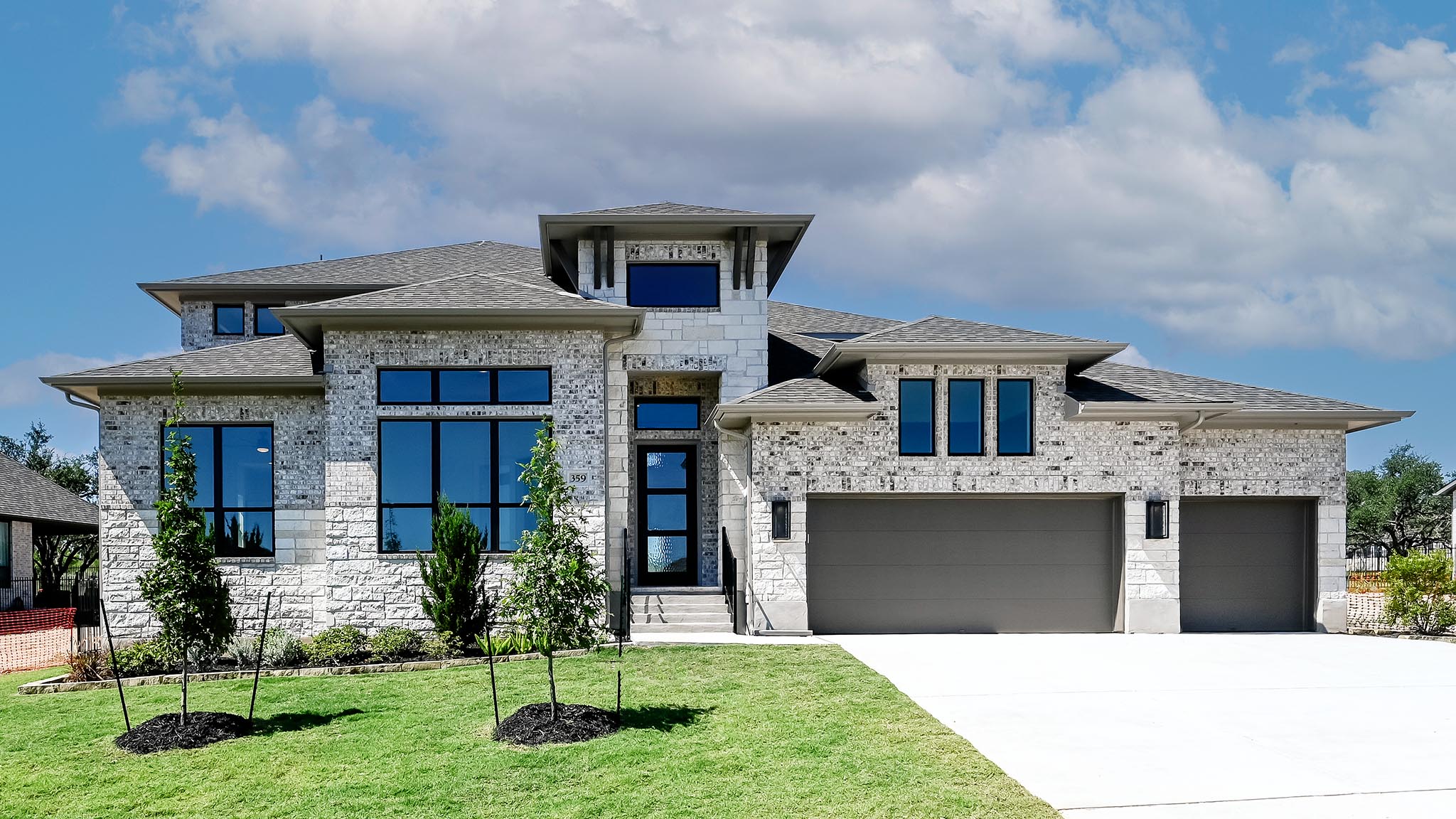 View of front of home featuring a shingled roof, driveway, a front lawn, and stone siding