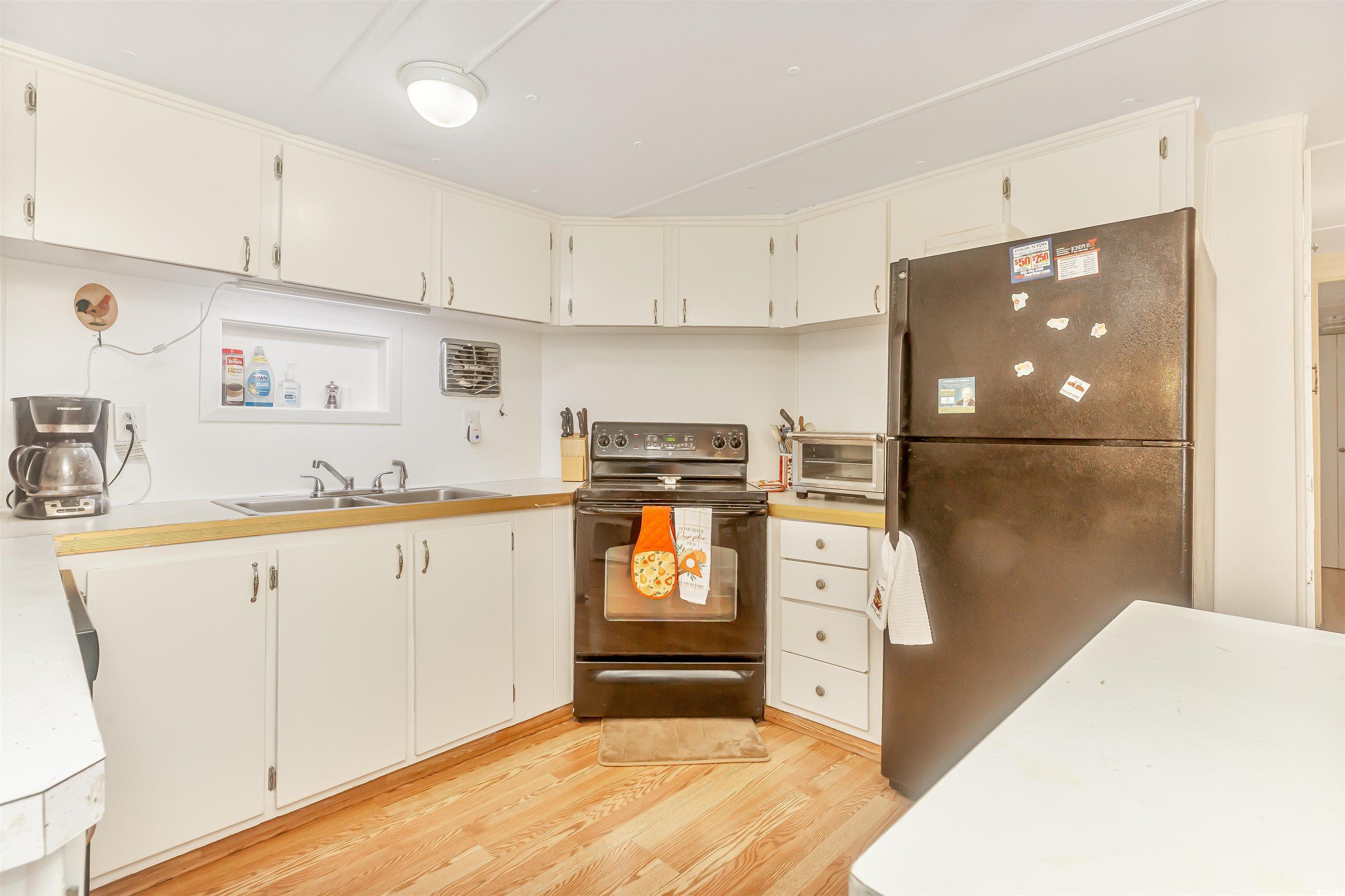 382 West Canal Street Murrells Inlet, SC 29576 - Photo 21 of 38 Kitchen with sink, light hardwood / wood-style flooring, white cabinets, and black appliances