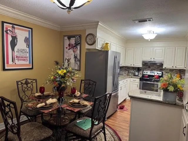 a kitchen with stainless steel appliances granite countertop a refrigerator and a dining table