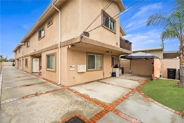 a view of a white house with a small yard and wooden fence