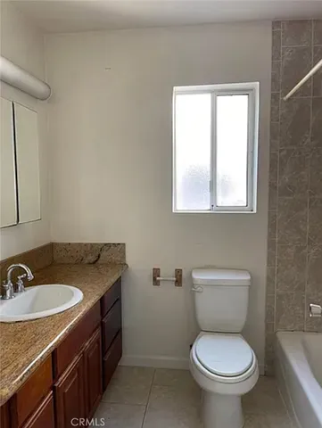 a bathroom with a granite countertop toilet a sink and a window