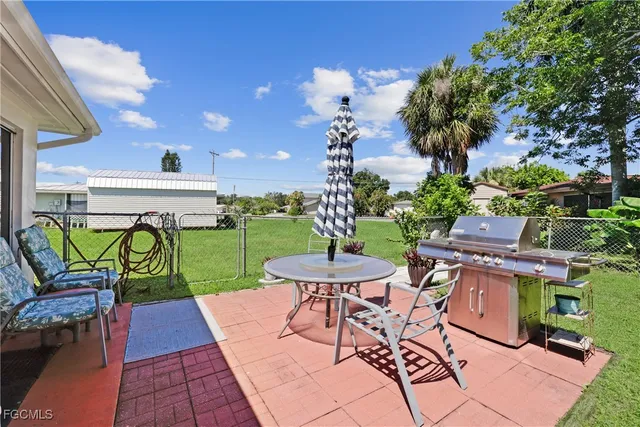 a view of a patio with table and chairs potted plants and a palm tree
