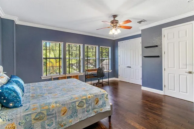 a bedroom with a bed and a large window with wooden floor