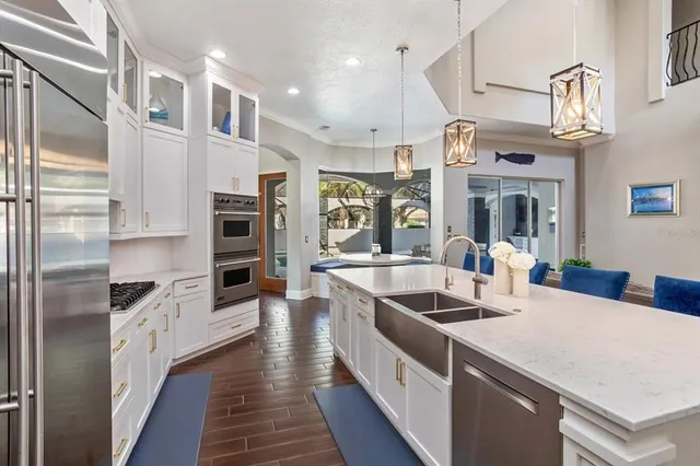 a kitchen with stainless steel appliances granite countertop a refrigerator a stove and a sink with wooden floor