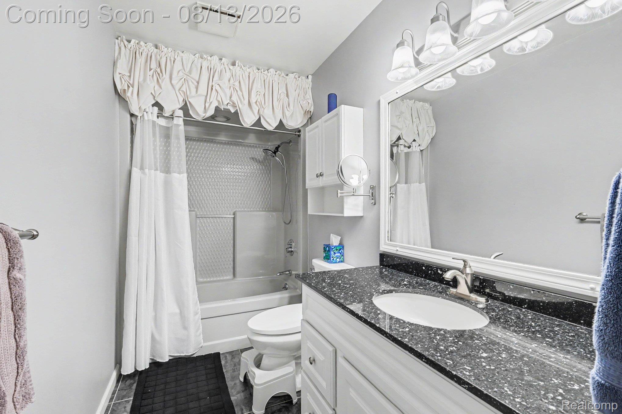 10361 Coldwater Road Flushing, MI 48433 - Photo 14 of 37 Bathroom featuring a single vanity with dark speckled countertop, integrated sink, and white cabinetry