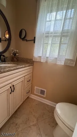 a bathroom with a granite countertop toilet sink and mirror