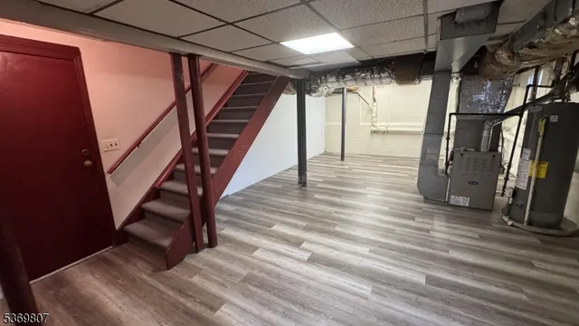 a view of an empty room with wooden floor and stairs