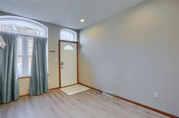 a view of an empty room with window and wooden floor