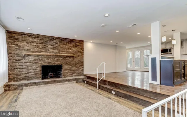 a living room with kitchen view and a fireplace