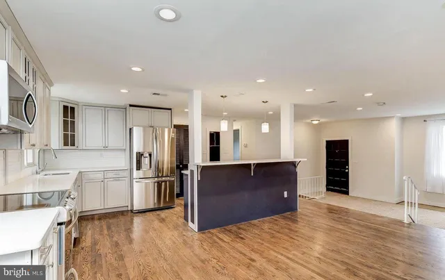 a kitchen with a sink a refrigerator and wooden floor