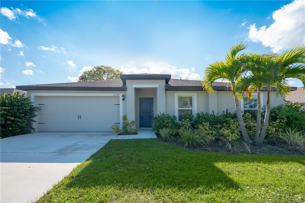 2108 Southwest Vista Road Port St. Lucie, FL 34953 - Photo 3 of 19 a front view of a house with a garden and plants