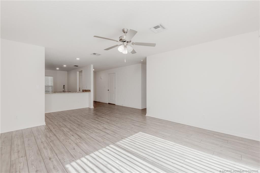 2108 Southwest Vista Road Port St. Lucie, FL 34953 - Photo 5 of 19 a view of an empty room with wooden floor and a ceiling fan