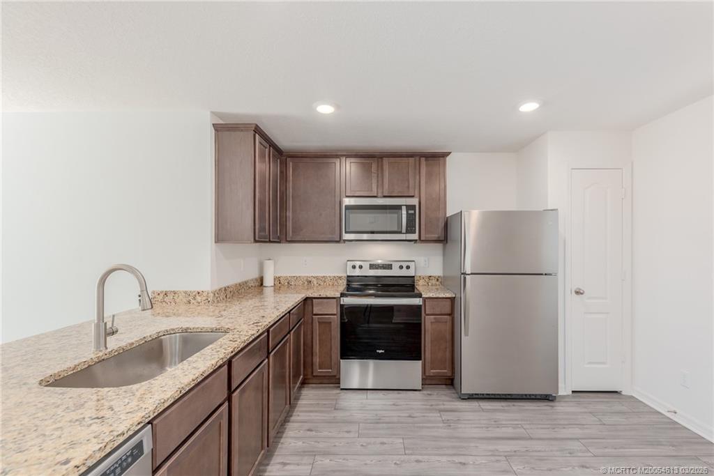 2108 Southwest Vista Road Port St. Lucie, FL 34953 - Photo 7 of 19 a kitchen with stainless steel appliances granite countertop a sink stove and refrigerator
