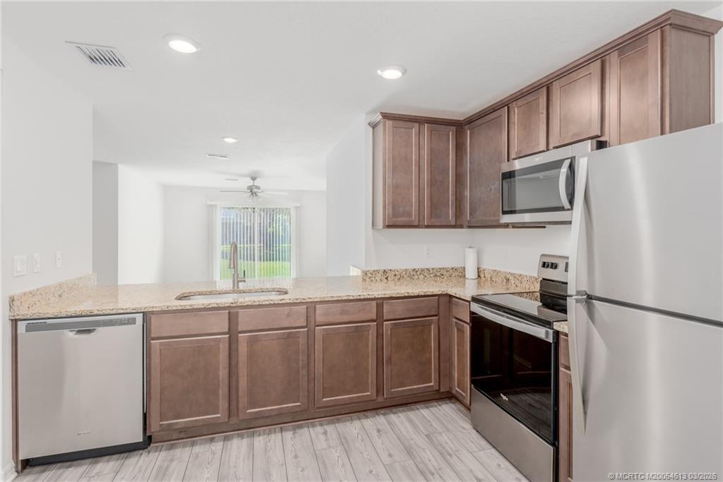 2108 Southwest Vista Road Port St. Lucie, FL 34953 - Photo 9 of 19 a kitchen with stainless steel appliances a sink cabinets and a wooden floor
