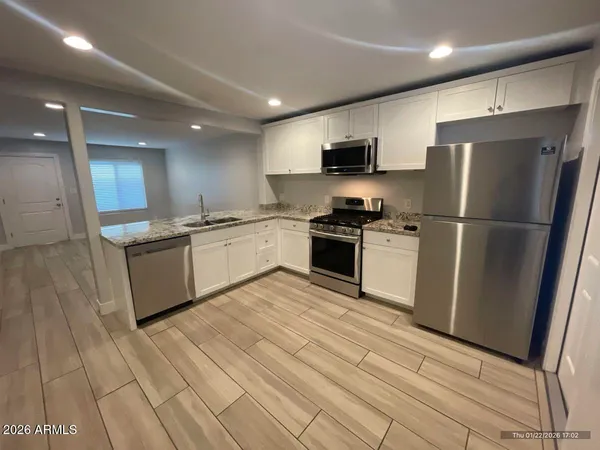 a kitchen with stainless steel appliances granite countertop a refrigerator a sink a stove and oven with wooden floor