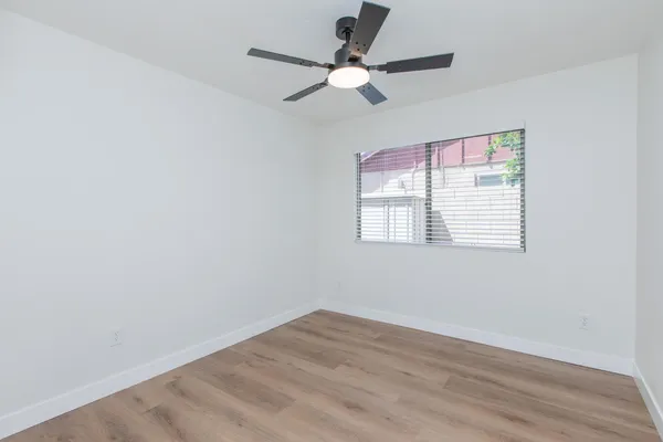 an empty room with wooden floor ceiling fan and windows