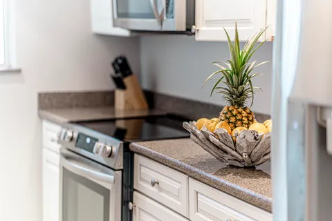 a kitchen with granite countertop a refrigerator a sink and white cabinets