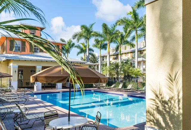 a small pool with lawn chairs under an umbrella