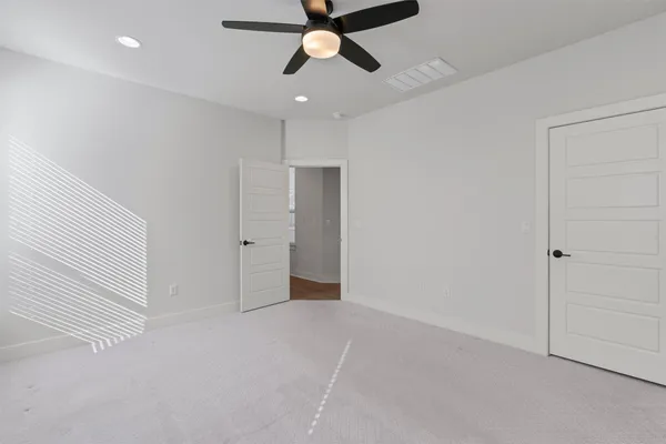 a view of an empty room and chandelier fan