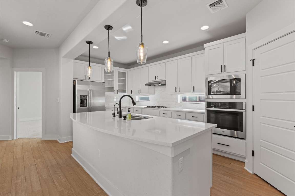 8707 Alderman Dr. Austin, TX 78747 - Photo 6 of 33 a kitchen with stainless steel appliances a sink a stove a refrigerator cabinets and wooden floor