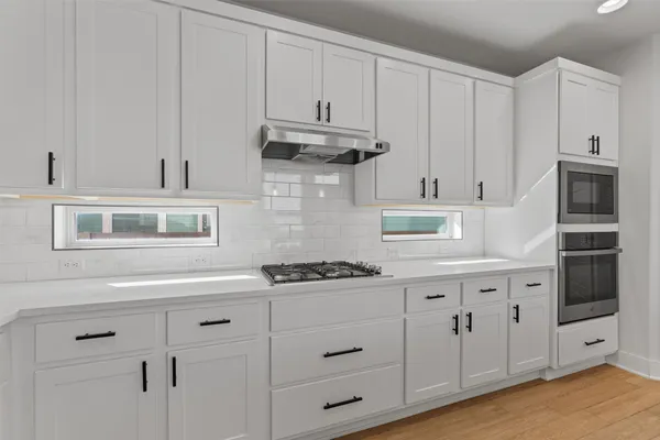 a kitchen with stainless steel appliances granite countertop white cabinets and a stove a oven with white countertops