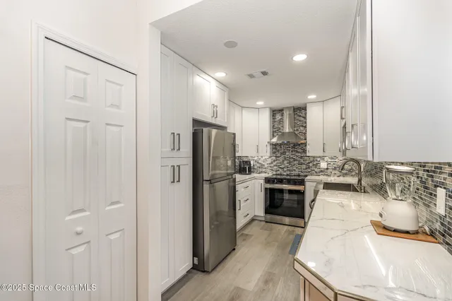a kitchen with stainless steel appliances kitchen island granite countertop a refrigerator and a sink
