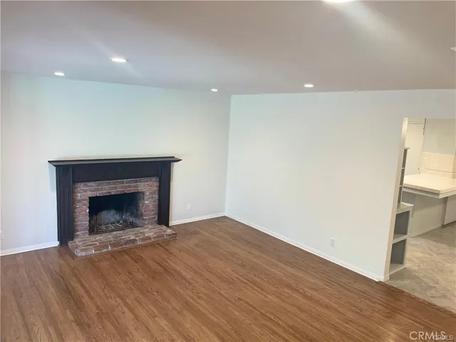 a view of empty room with wooden floor and fireplace