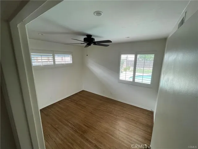 an empty room with windows and fan