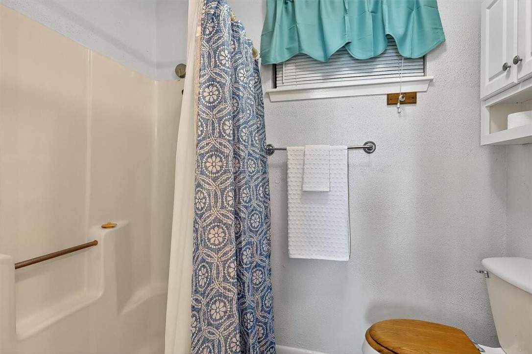 3402 Ocean Drive Corpus Christi, TX 78411 - Photo 22 of 39 a bathroom with a toilet and a shower curtain