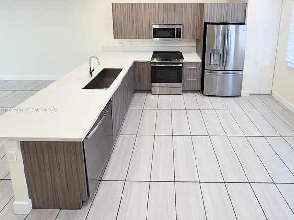 a kitchen with stainless steel appliances a sink a stove a refrigerator and cabinets