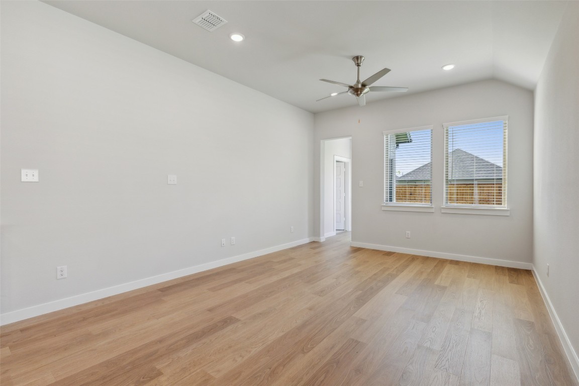 153 Tolo Drive Elgin, TX 78621 - Photo 6 of 25 an empty room with wooden floor ceiling fan and windows