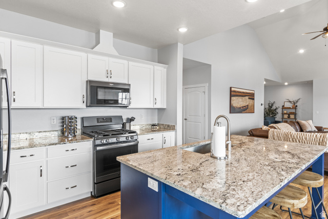 1343 North Trapper Loop Garden City, UT 84028 - Photo 56 of 56 Two tone kitchen featuring stainless steel appliances, open floor plan, light stone countertops, light wood-type flooring, and a kitchen island with sink