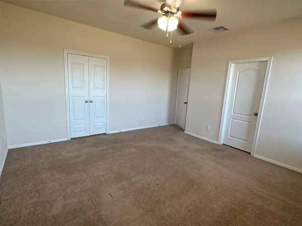an empty room with a chandelier fan and closet area