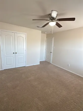 a view of an empty room and chandelier fan