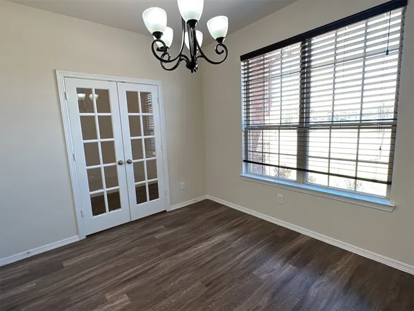 a view of an empty room with wooden floor and windows