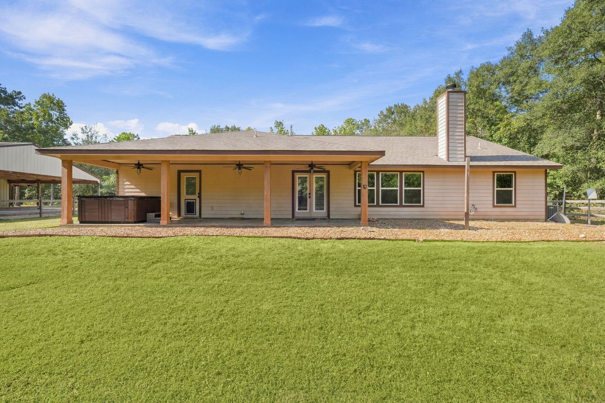 7049 Pine Shadows Road Cleveland, TX 77328 - Photo 31 of 49 a spacious covered patio,a hot tub, ceiling fans, and a cozy outdoor area perfect for relaxation and entertainment.