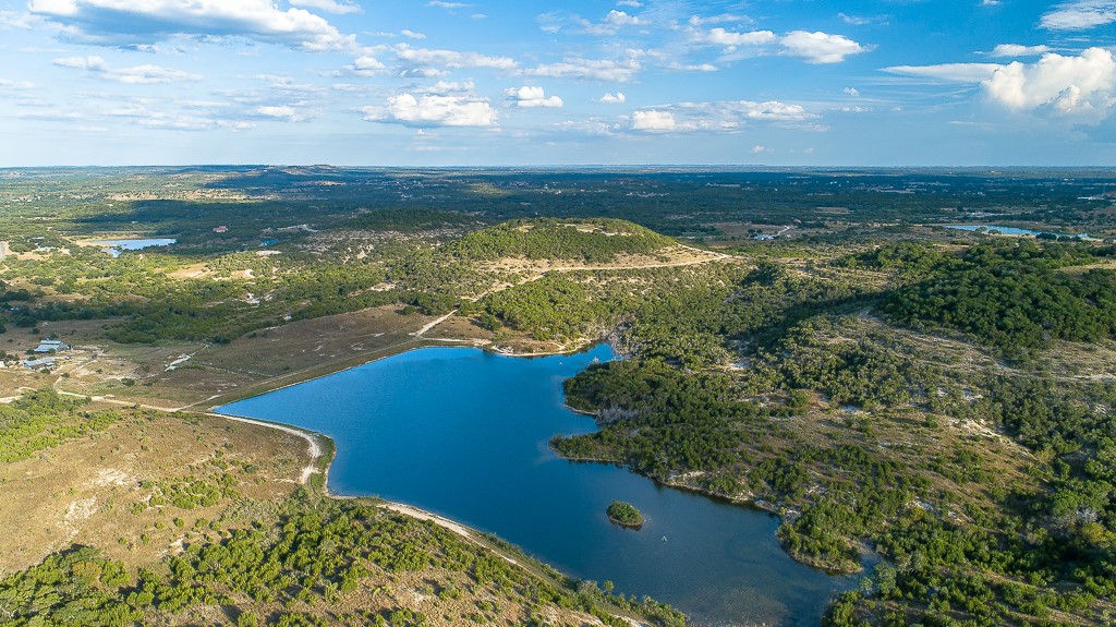 717 Bluff Ridge Trail Blanco, TX 78606 - Photo 18 of 21 A sprawling landscape reveals a pristine lake nestled amidst rolling hills and lush vegetation.