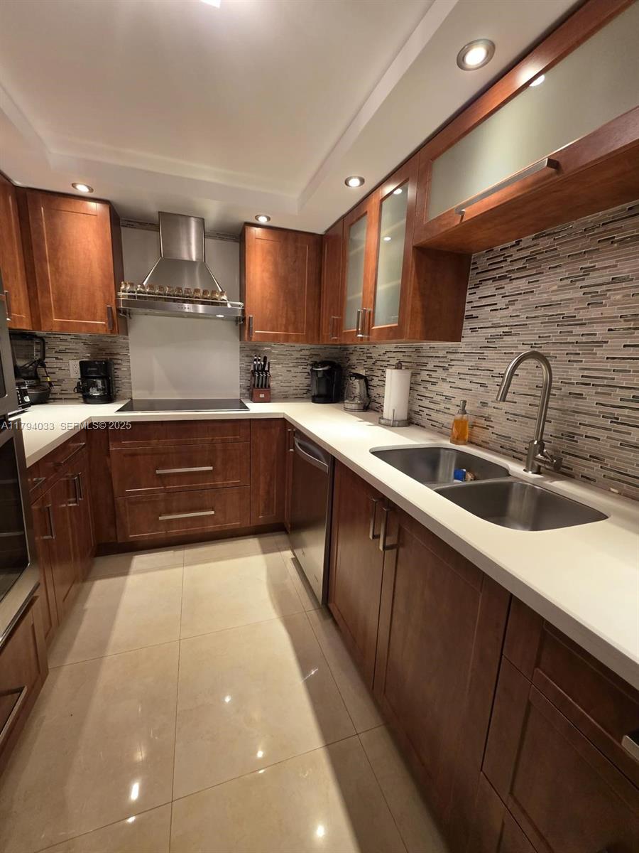 9225 Collins Avenue, Unit 1409 Surfside, FL 33154 - Photo 13 of 41 a kitchen with stainless steel appliances a sink dishwasher a stove top oven a refrigerator with wooden cabinets and floor