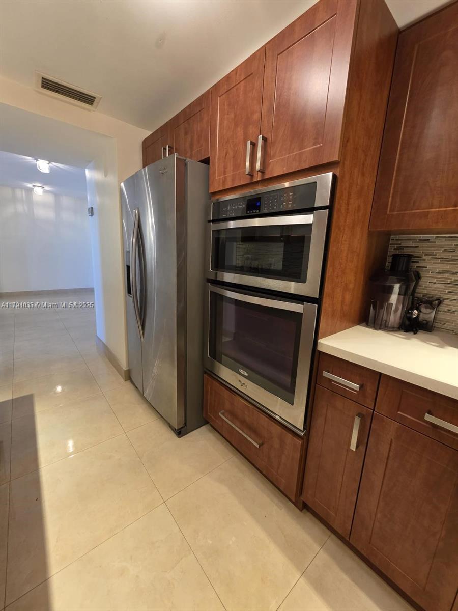 9225 Collins Avenue, Unit 1409 Surfside, FL 33154 - Photo 15 of 41 a kitchen with granite countertop stainless steel appliances and wooden cabinets