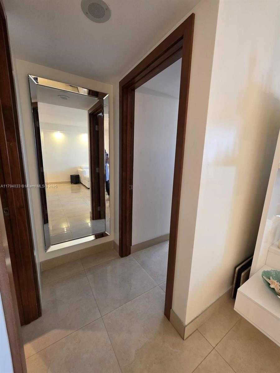 9225 Collins Avenue, Unit 1409 Surfside, FL 33154 - Photo 16 of 41 a view of a hallway with wooden floor and a bathroom