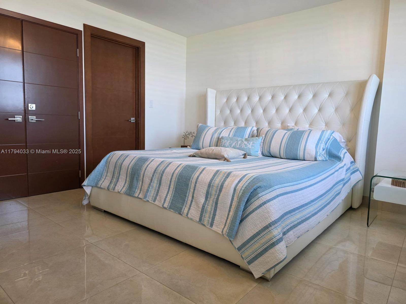 9225 Collins Avenue, Unit 1409 Surfside, FL 33154 - Photo 18 of 41 a bedroom with a bed and a table