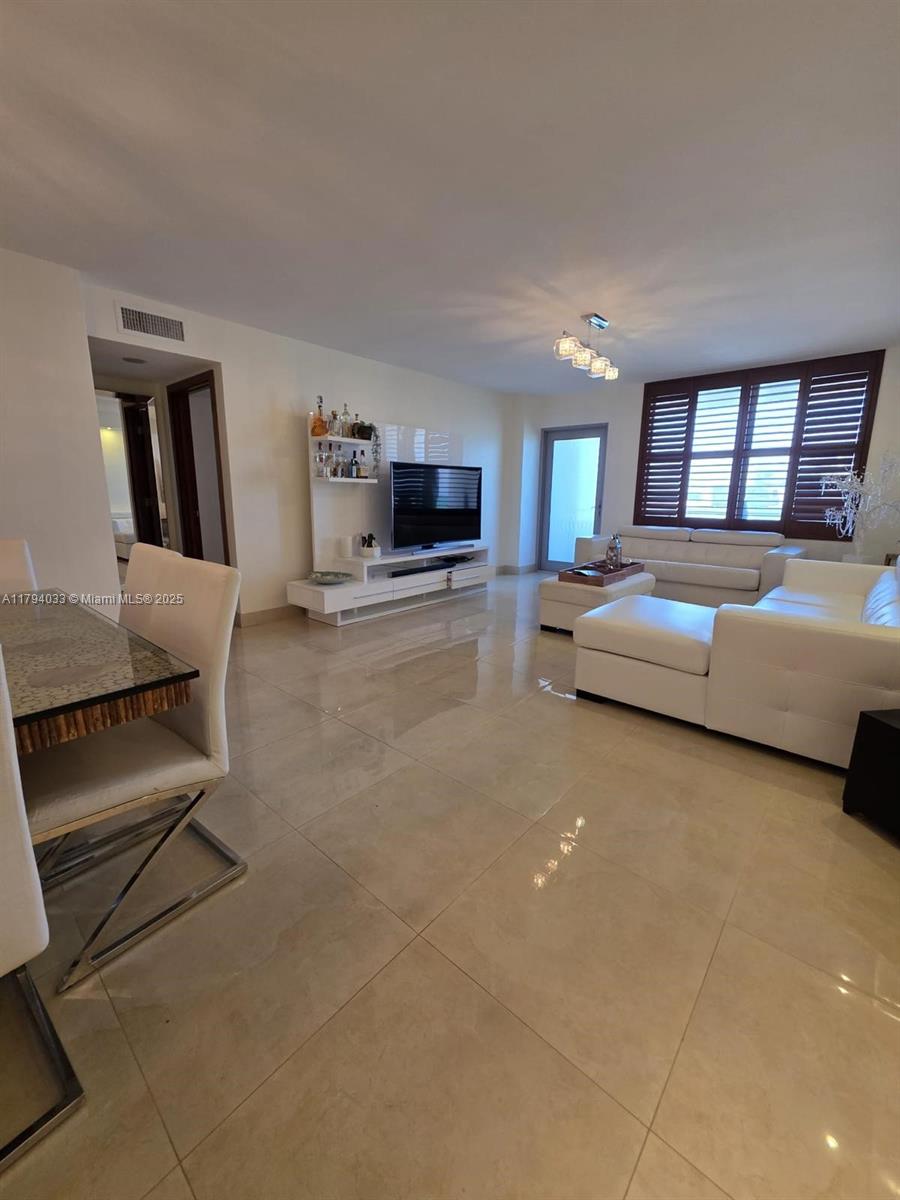 9225 Collins Avenue, Unit 1409 Surfside, FL 33154 - Photo 2 of 41 a living room with furniture and a flat screen tv