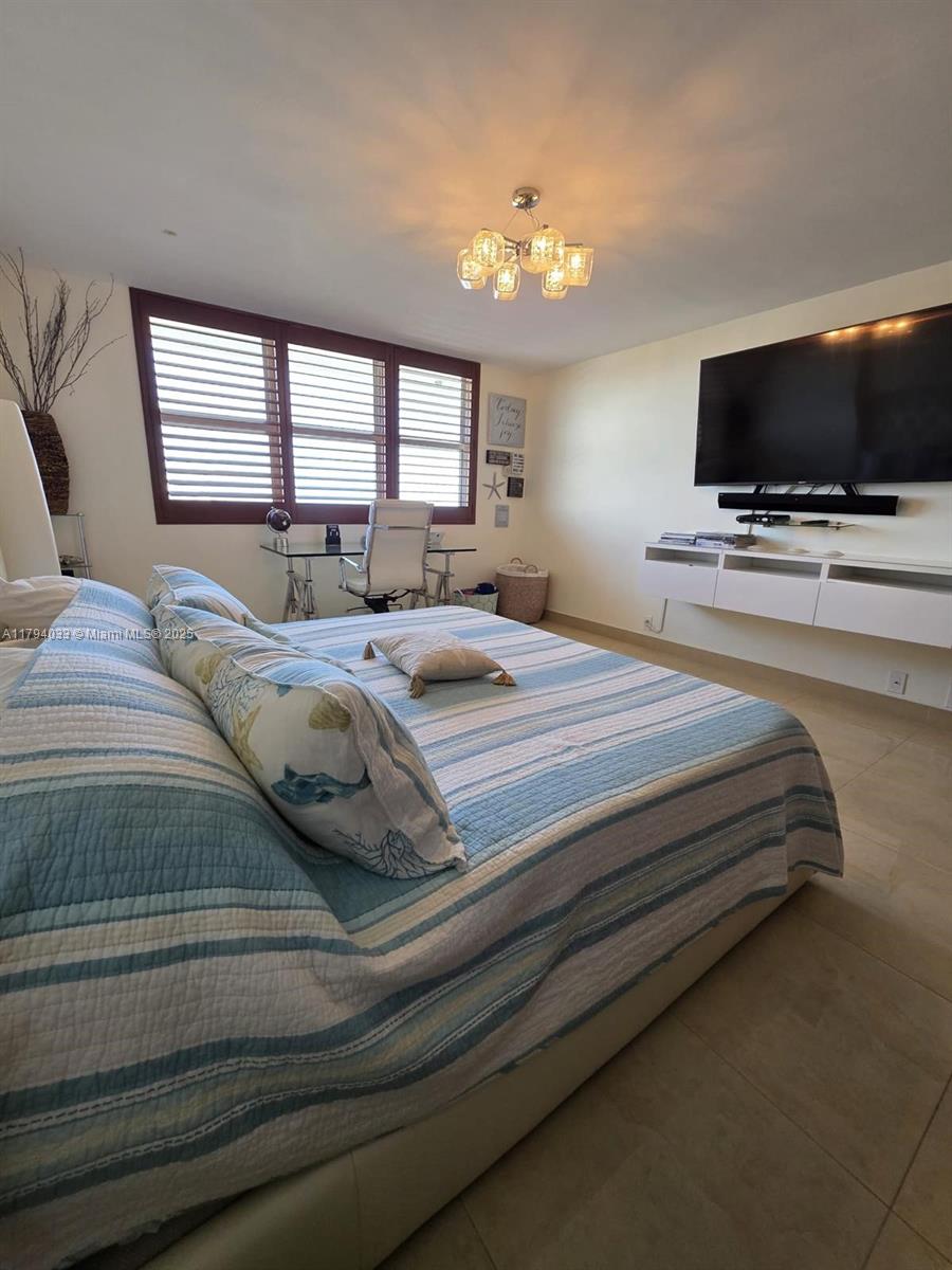 9225 Collins Avenue, Unit 1409 Surfside, FL 33154 - Photo 23 of 41 a bedroom with a bed and a flat screen tv
