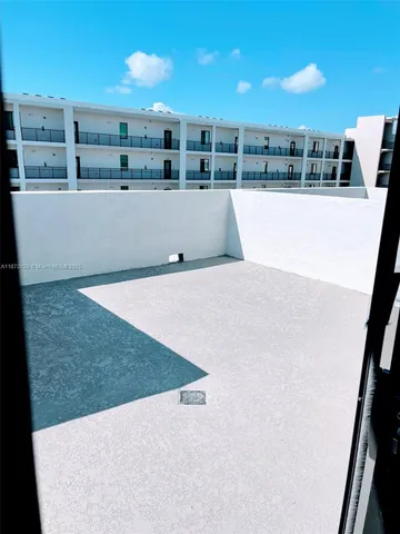 a view of a swimming pool with lawn chairs potted plants and palm tree