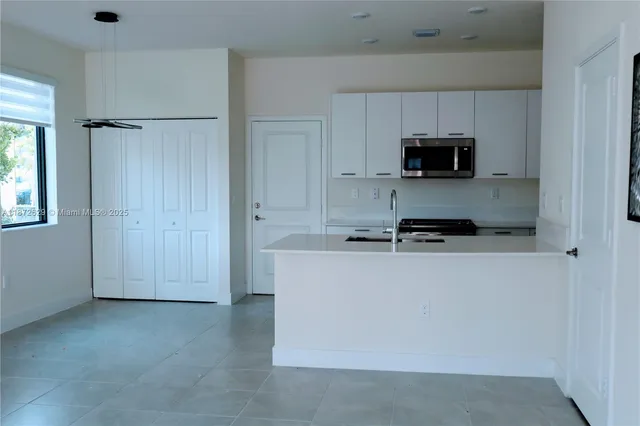 a kitchen with stainless steel appliances a stove a microwave and white cabinets