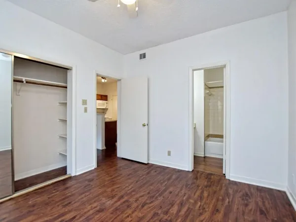 an empty room with wooden floor & closet area