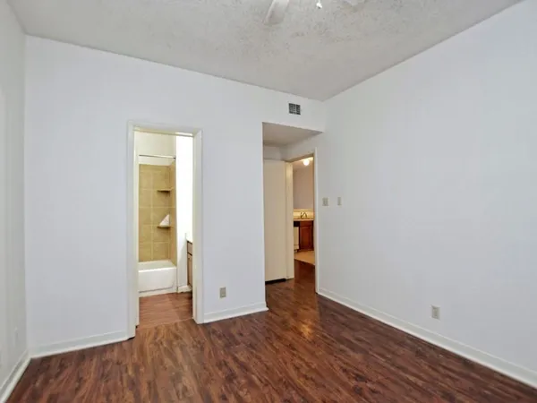 a view of an empty room with closet and wooden floor