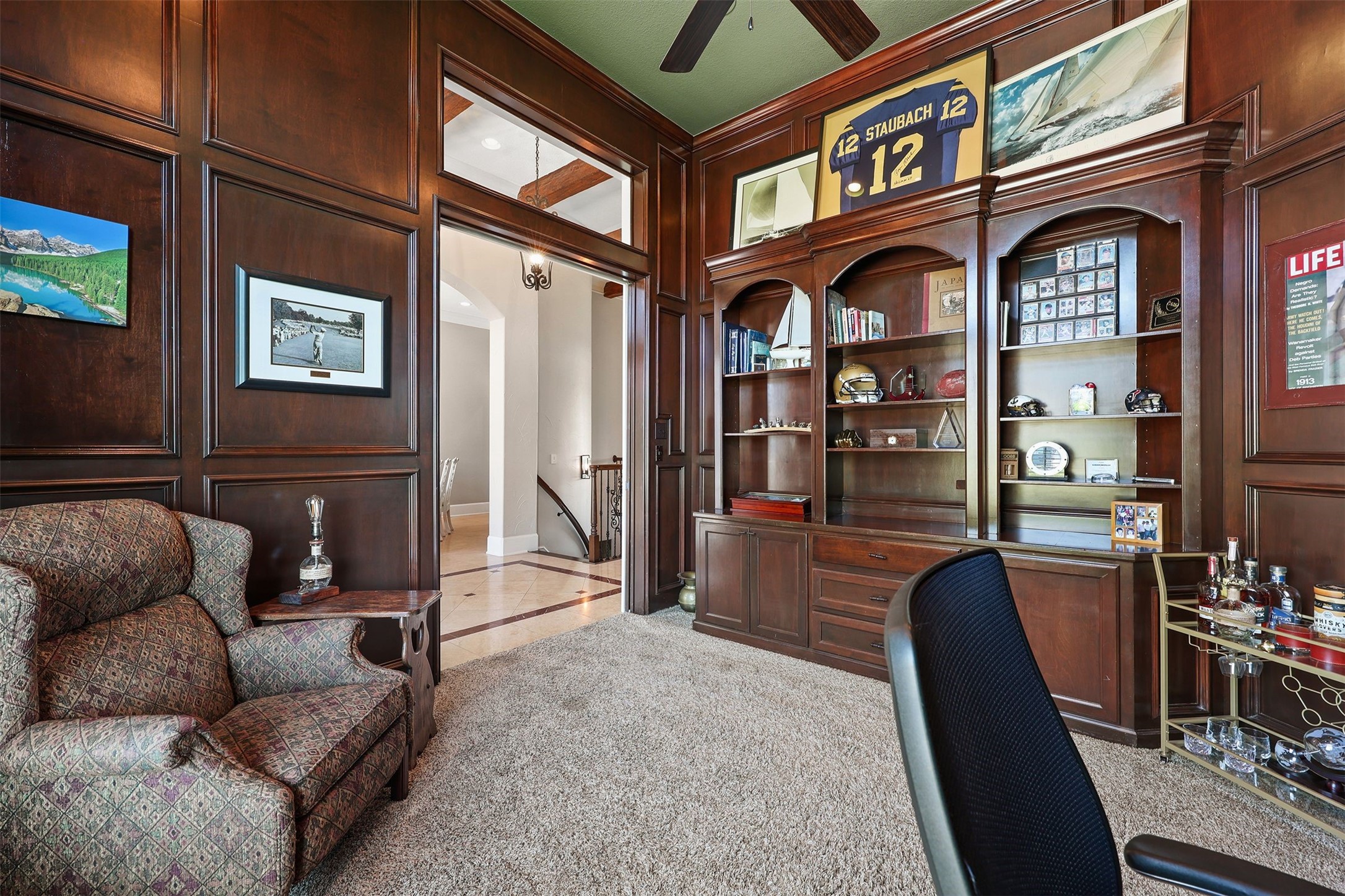10896 Decatur Street Willis, TX 77318 - Photo 14 of 50 This elegant home office exudes sophistication with its rich wood paneling, ample built-in shelving, and plush carpeting, offering a warm and inviting atmosphere perfect for productivity and relaxation.