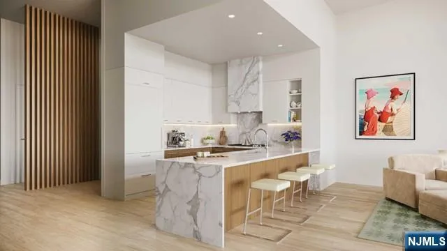 a living room with stainless steel appliances furniture a rug and a kitchen view
