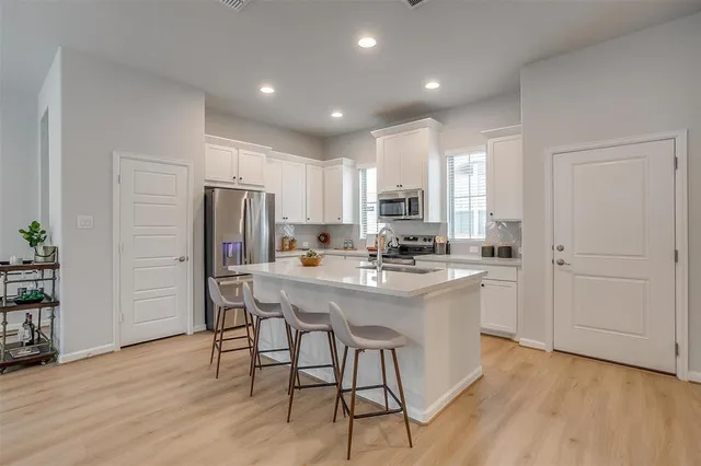 a kitchen with stainless steel appliances a refrigerator a stove a sink cabinets and wooden floor